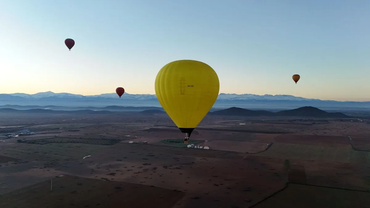 Yellow balloon flying over Marrakech with Atlas Mountains panorama
